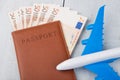 plane, passport and paper money on white wooden table
