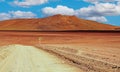 Adventure travel in life hostile arid dry barren landscape: Empty sandy dirt track, red desert mountains, lonely sharp curve left