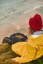 Adventure trip in cold season. Close up of travel girl in yellow jacket and warm hat sitting on the top of rock and Royalty Free Stock Photo