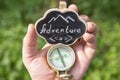 Adventure waiting for you concept - small sign with Adventure inscription and compass in a hand