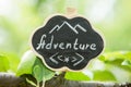 Adventure waiting for you concept - small sign with Adventure inscription outdoors, green blurred background