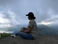 Adventure woman sitting on a concrete, with a hot morning coffee cup or tea in hand enjoying the top of mountain view. Royalty Free Stock Photo