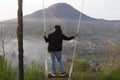 Adventure woman standing on natural wooden swing, enjoying misty mourning view in the morning. Person relax on swing.