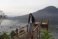 Woman walking alone on a natural wooden bridge. On blue mountain view background at sunrise on misty morning