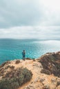 Adventurer with a backpack stands on the edge of a cliff and observes the beautiful group of yellow-gold rocks of Punta de la