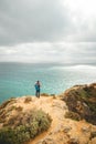 Adventurer with a backpack stands on the edge of a cliff and observes the beautiful group of yellow-gold rocks of Punta de la