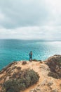 Adventurer with a backpack stands on the edge of a cliff and observes the beautiful group of yellow-gold rocks of Punta de la