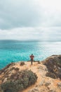 Adventurer with a backpack stands on the edge of a cliff and observes the beautiful group of yellow-gold rocks of Punta de la