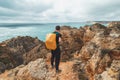 Adventurer with a backpack stands on the edge of a cliff and observes the beautiful group of yellow-gold rocks of Punta de la