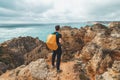 Adventurer with a backpack stands on the edge of a cliff and observes the beautiful group of yellow-gold rocks of Punta de la