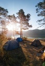 Adventures Camping tourism and tents under the view pine forest landscape near water outdoor in morning sky. Summer travel and Royalty Free Stock Photo