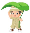 an adventurous boy walks with a large leaf as an umbrella