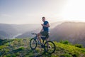 Adventurous Cyclist riding his mountain bike at the edge of a cliff, on rocky terrain while wearing no safety equipment.Amazing