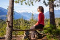 Adventurous Female Hiker is sitting on a bench and enjoying the beautiful Canadian Mountain Landscape