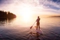 Adventurous girl on a paddle board is paddeling in the Pacific West Coast Ocean Royalty Free Stock Photo