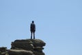 Adventurous hiker standing on top of the cliff and looking at the sky