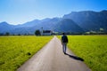 Adventurous hiker walking on the road leading to the beautiful mountains covered in greens