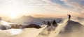 Adventurous Man Hiker with ice axe standing on top of peak with rocky mountain in background. Royalty Free Stock Photo