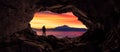 Adventurous Man Hiker standing in a cave. Fog and Mountains in background.