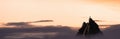 Adventurous Man Hiker Standing on top of a rocky mountain overlooking the dramatic landscape at sunset.