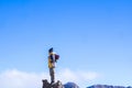 Adventurous man hiker in warm clothing and knit hat with backpack standing on top of rocky mountain peak admiring scenic beauty of Royalty Free Stock Photo
