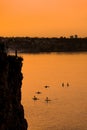 Adventurous people on a stand up paddle board is paddling during a bright and vibrant sunrise