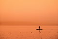 Adventurous people on a stand up paddle board is paddling during a bright and vibrant sunrise Royalty Free Stock Photo