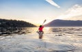 Adventurous Woman on Sea Kayak paddling in the Pacific Ocean. Sunny Summer Sunset