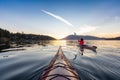 Adventurous Woman on Sea Kayak paddling in the Pacific Ocean. Sunny Summer Sunset