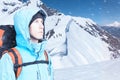 Adventurous young man with backpack standing on mountain top view and looking out. Snowboarders walking uphill for