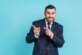 Advertise here. Positive bearded man wearing official style suit pointing finger away paying your Royalty Free Stock Photo