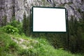 Advertising billboard with empty white mockup in green forest of mountains. Royalty Free Stock Photo