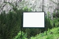 Advertising billboard with empty white mockup in green forest of mountains. Royalty Free Stock Photo