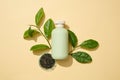 Advertising scene with a bottle mockup for cosmetic with green tea leaves on beige background Royalty Free Stock Photo