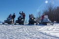 Young happy men, women and children on the snowmobiles Yamaha on a snowy slope winter Sunny day