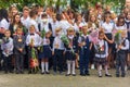 Children enrolled in the first class with bouquets of flowers in the hands and high school students on the school solemn parade