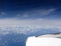 Aerial above the clouds with the wing of a commercial jet plane Jet with the Pacific Ocean Royalty Free Stock Photo