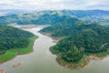 Aerial above view green mountain forest and dam reservoir river in the rain season and curved road on the hill connecting Royalty Free Stock Photo
