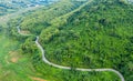 Aerial above view green mountain forest in the rain season and curved road on the hill connecting countryside Royalty Free Stock Photo