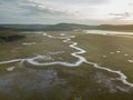 Aerial above a winding river in a wetland at sunrise