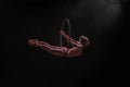 Aerial acrobat in the air ring. Young woman performs the acrobatic elements in the air hoop. Aerialist in on black Royalty Free Stock Photo