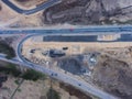 Aerial air view of a massive construction site with a heavy vehicle, bulldozer and excavator, building a new road, working and unl