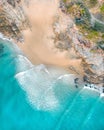 Aerial of a beach with beautiful waves, white sand and rocks at sunset