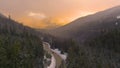 AERIAL: Evening sunshine illuminates the way for car driving down scenic road Royalty Free Stock Photo