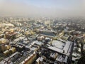 Aerial black and white winter top view of modern city center with tall buildings and parked cars on snowy streets