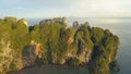 AERIAL: Breathtaking limestone cliff is illuminated by the golden rising sun.