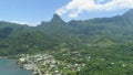 AERIAL: Breathtaking mountains overgrown by jungle surround coastal village.