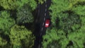 Aerial camera following red car driving on a curvy forest road. 3D rendering Royalty Free Stock Photo