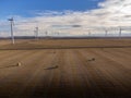 Aerial Canadian windmills with round bales of hay on a harvested field near Pincher Creek Alberta Canad