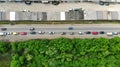 Aerial. Cars traffic on the asphalt road between green forest and garages.